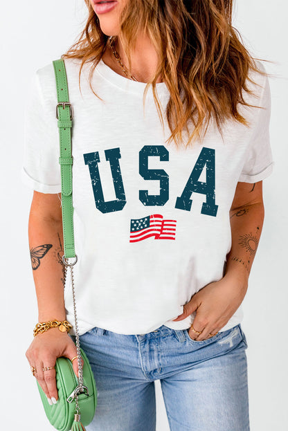 Woman in casual white USA print t-shirt, light denim jeans, accessorized with green cross-body bag and gold jewelry, showcasing a relaxed, patriotic style.