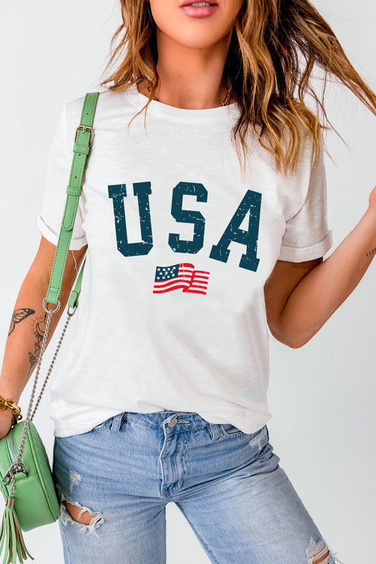 Woman in a USA graphic tee with an American flag, paired with distressed jeans and a green shoulder bag, epitomizing casual American fashion.