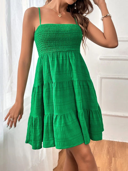 A woman models a vibrant green tiered sundress with a shirred bodice, paired with delicate jewelry, evoking fresh summer style. Perfect for seasonal fashion content.