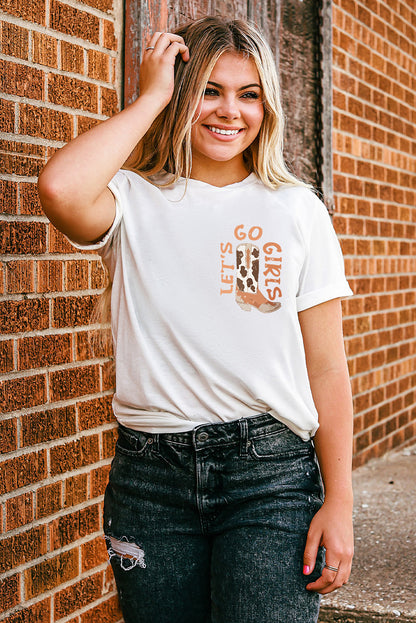 Blonde woman in a casual white graphic tee and ripped black jeans posing against a brick wall, embodying a relaxed, trendy urban style.