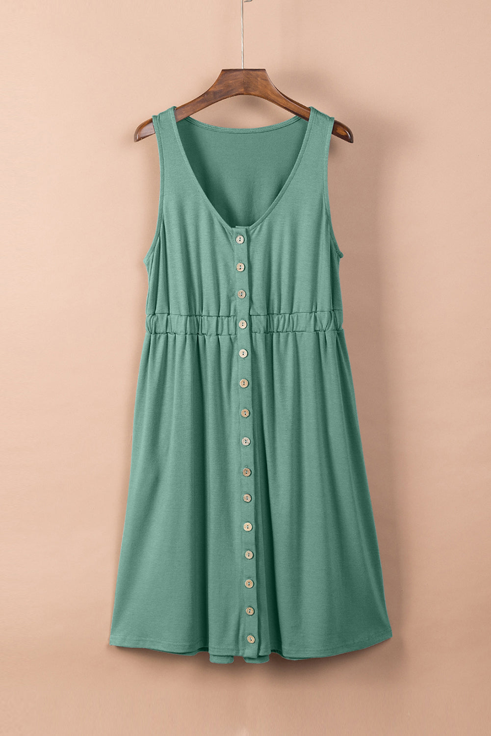 Elegant sleeveless green summer dress with front buttons and gathered waist, displayed on a wooden hanger against a neutral backdrop—perfect for casual outings and warm weather.