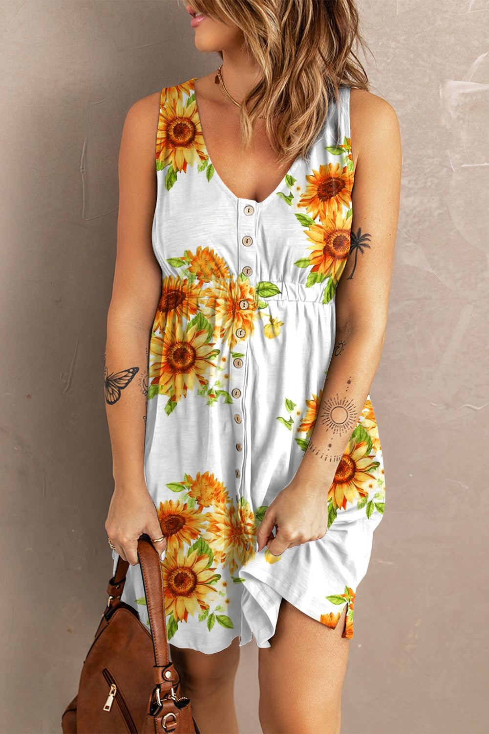 Woman in a sleeveless floral dress holding a brown leather bag, showcasing a casual summer style with button details and sunflower print.