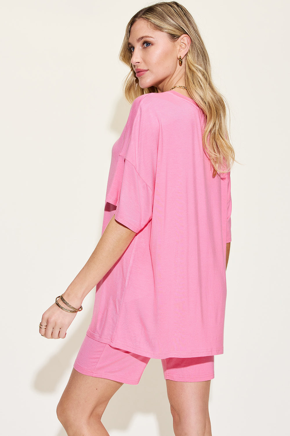 Woman modeling a vibrant pink t-shirt dress with casual loose fit, perfect for the spring and summer seasons, showcasing comfort and style.